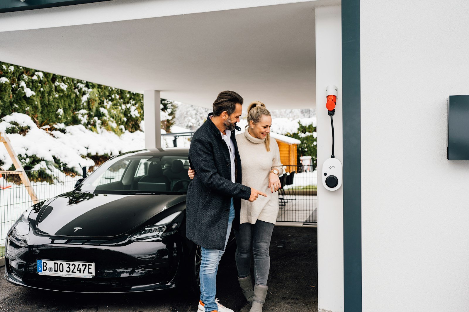 Couple charging an electric car on a Hazlehead driveway