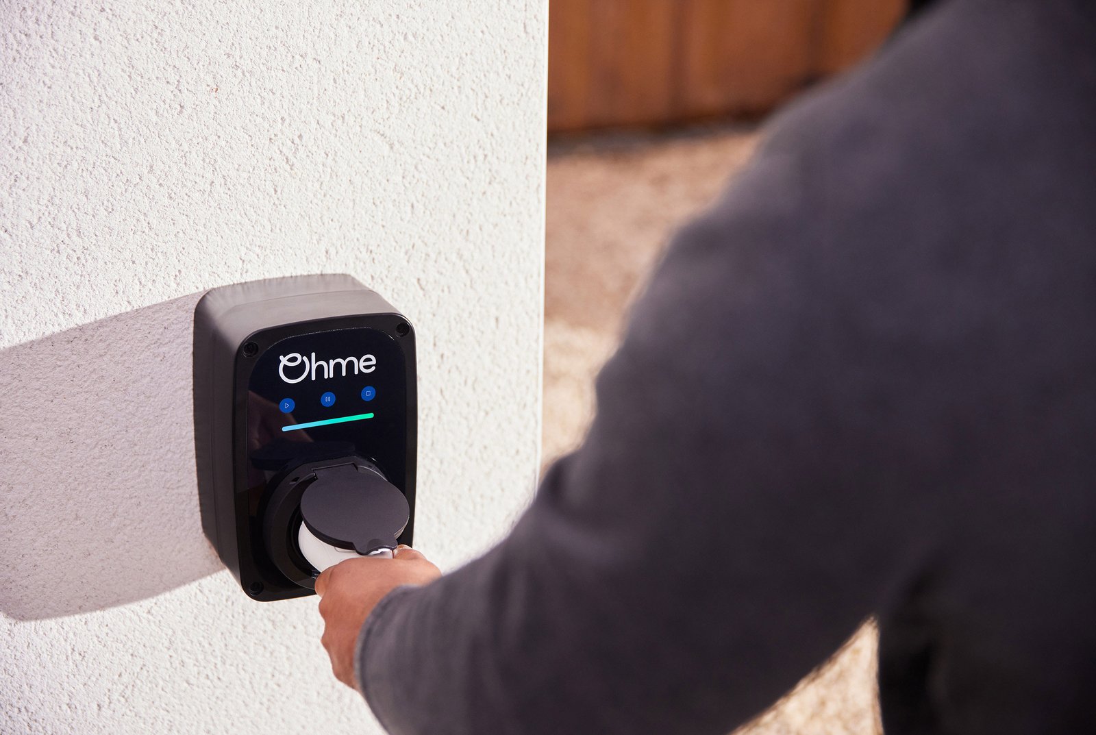 Driver plugging into a wall mounted Ohme ePod EV charger on a Loirston driveway