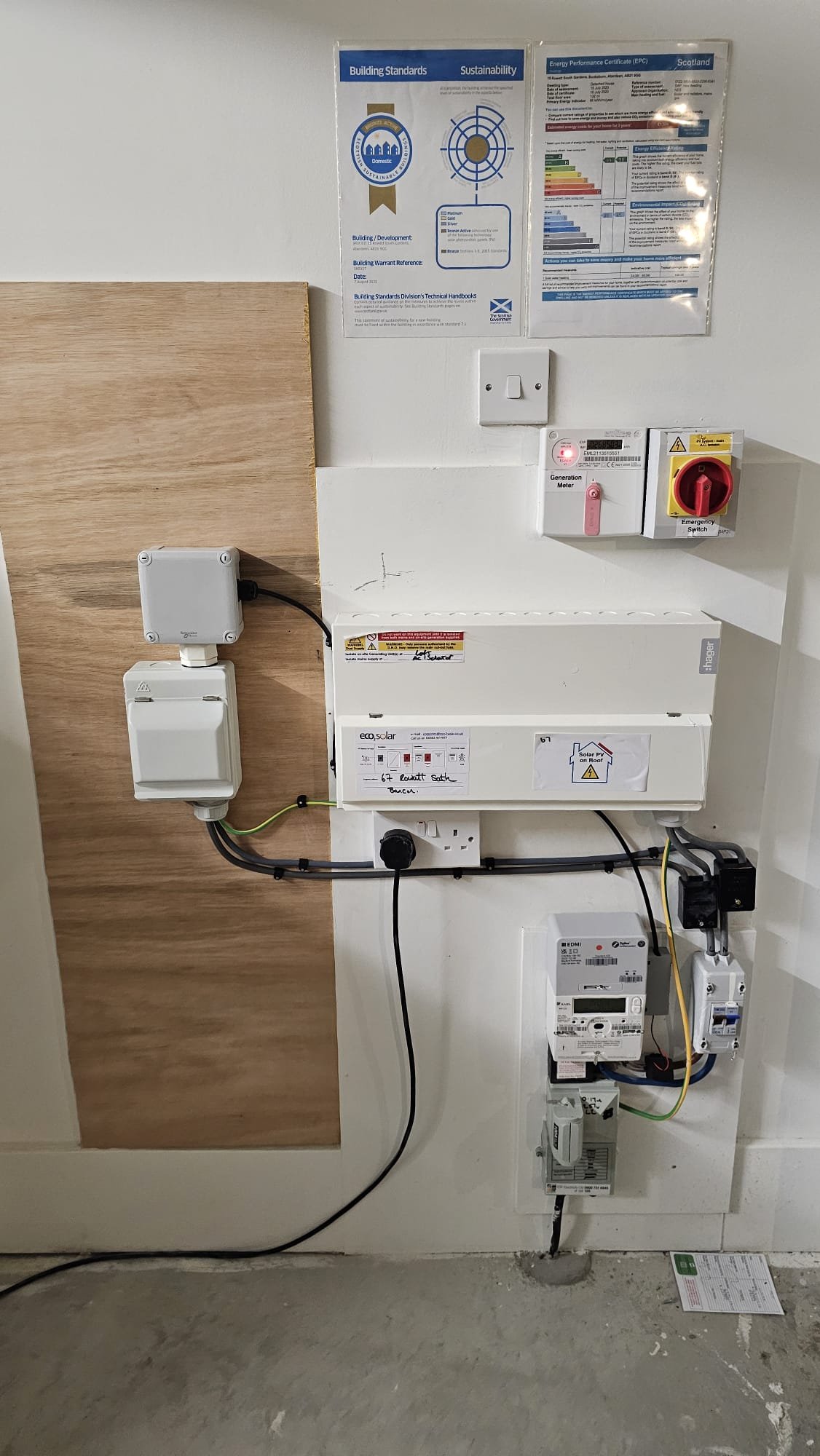 Solar PV and EV charger setup at a new-build Aberdeenshire home. EcoSolar inverter, generation meter, smart meter, emergency switch and Scottish EPC documentation