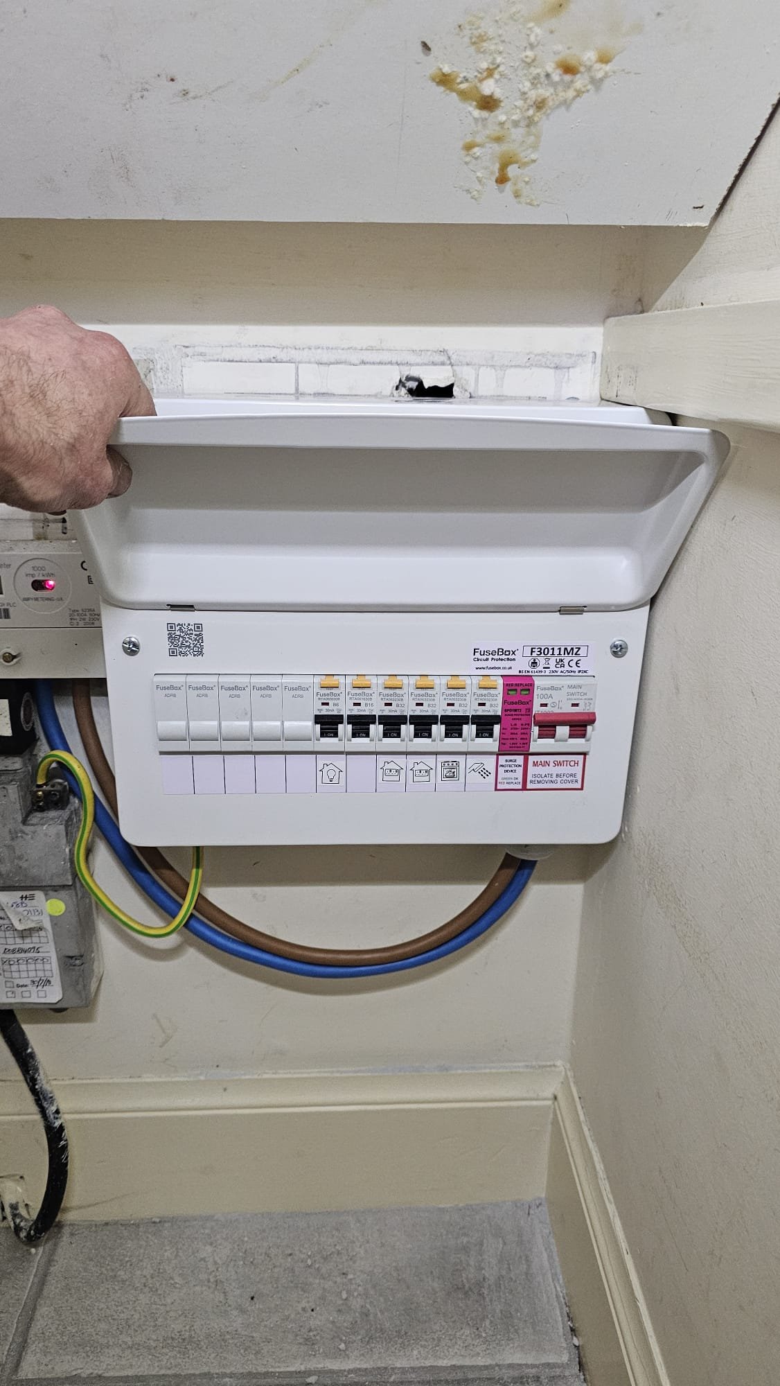 Under-stair consumer unit replacement in Aberdeen mid-changeover. Old supply cable still trailing before final connection