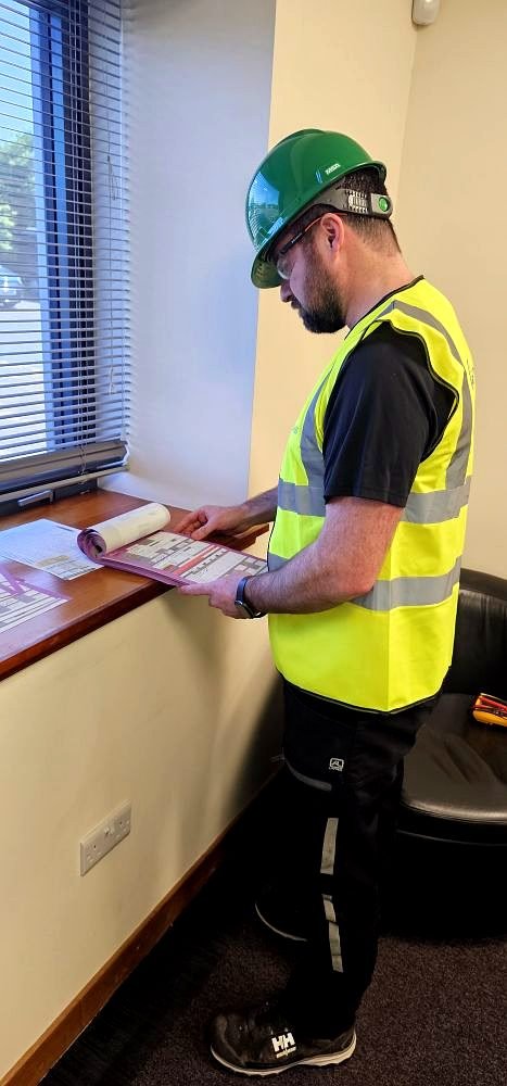 NICEIC approved electrician reviewing electrical certification paperwork on site