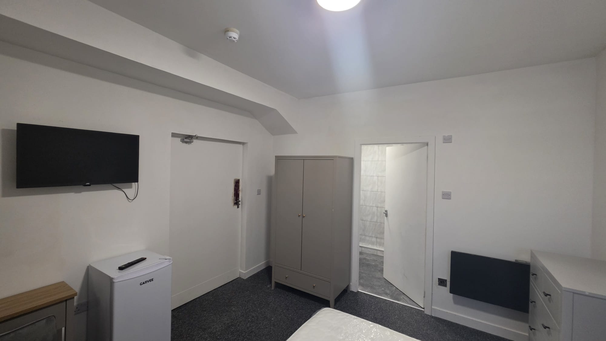 Peterhead accommodation room with a fire door on a closer, a wall mounted electric panel heater and a television point