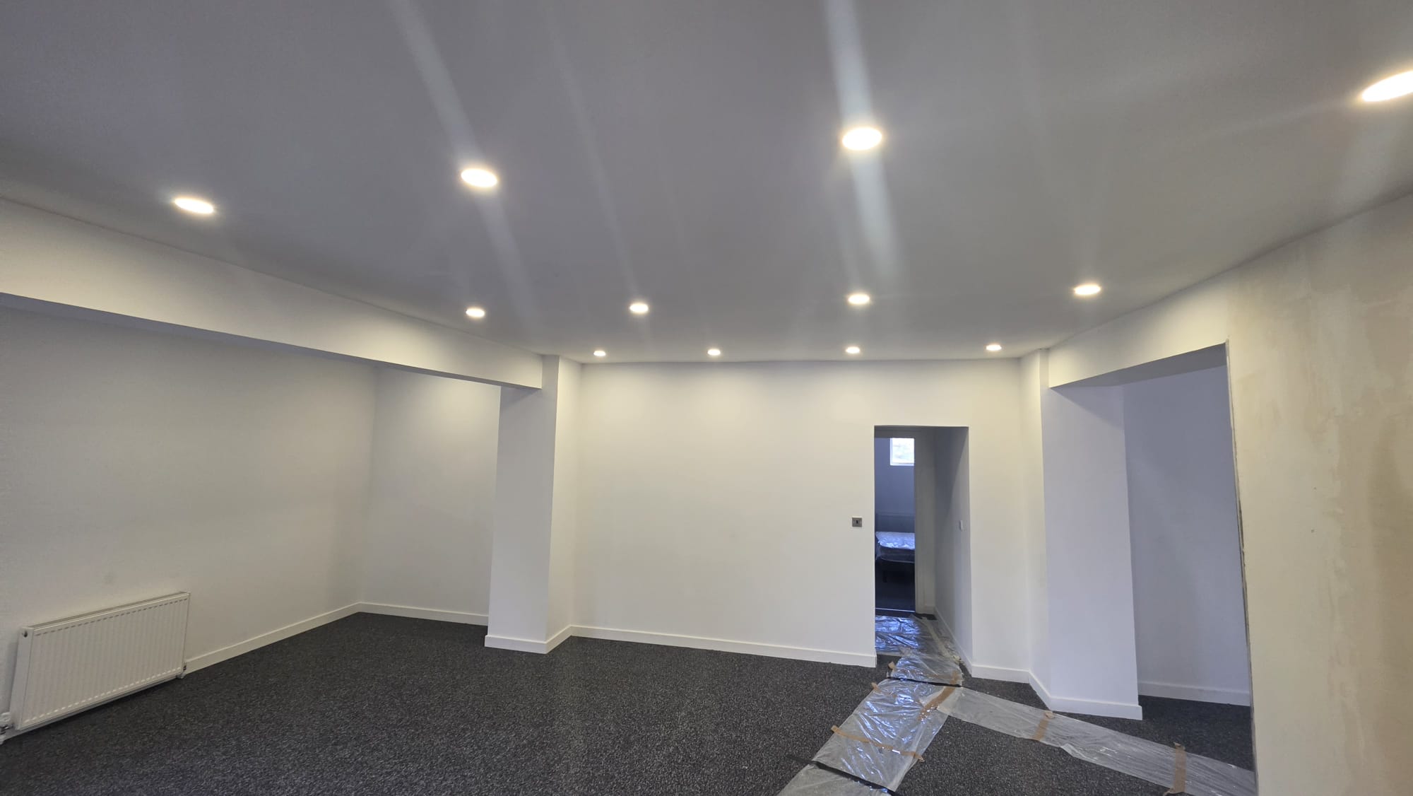 LED downlight installation across a commercial ceiling during a fit out, with floor protection still in place