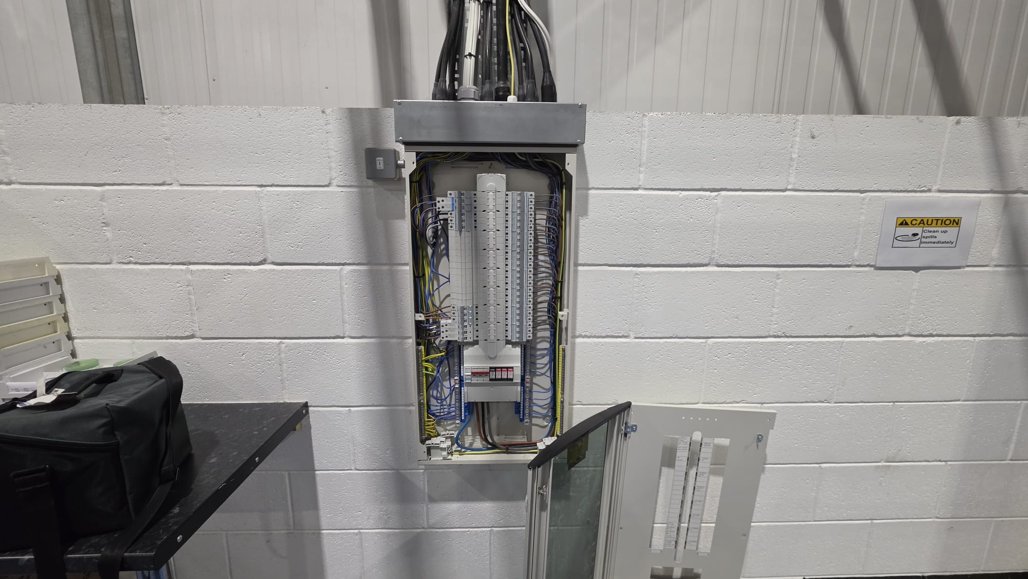Aberdeen commercial distribution board with the cover removed for EICR inspection and the test kit beside it
