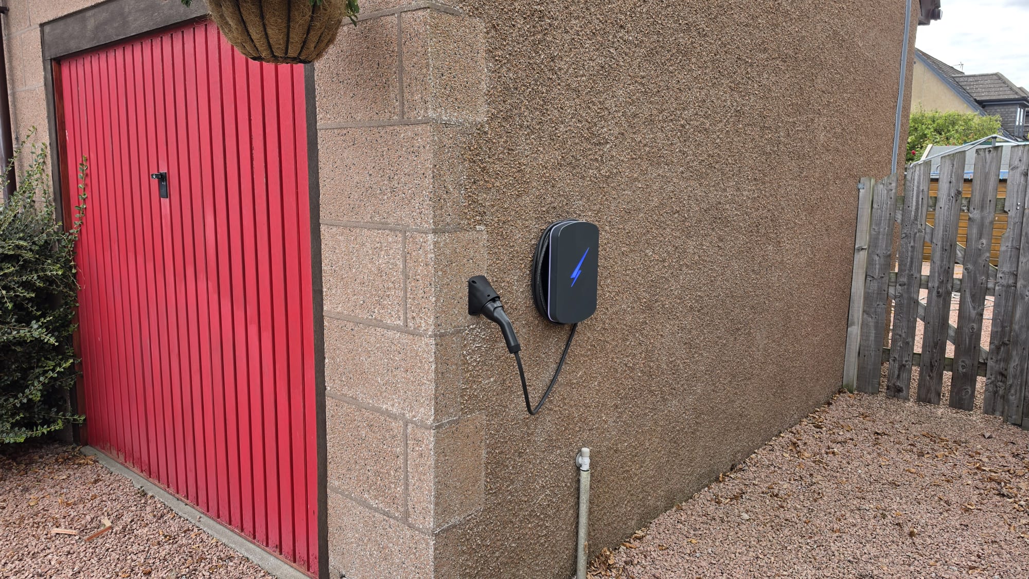 Hypervolt EV charger fitted to a rendered garage wall beside a red garage door in Kintore