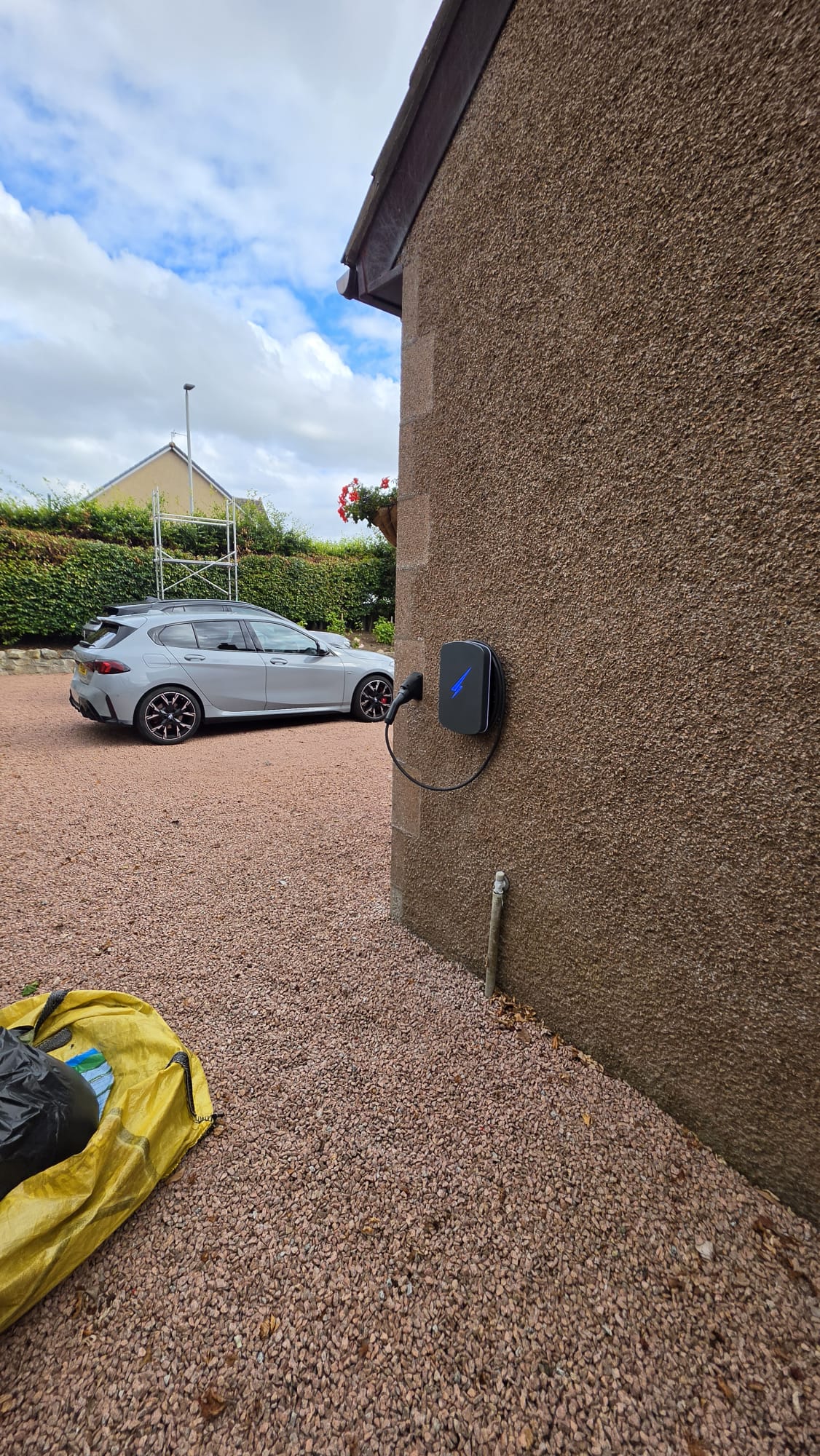 Hypervolt EV charger mounted at parking height on a pebbledash gable wall beside a gravel driveway in Kintore, with a car parked beyond