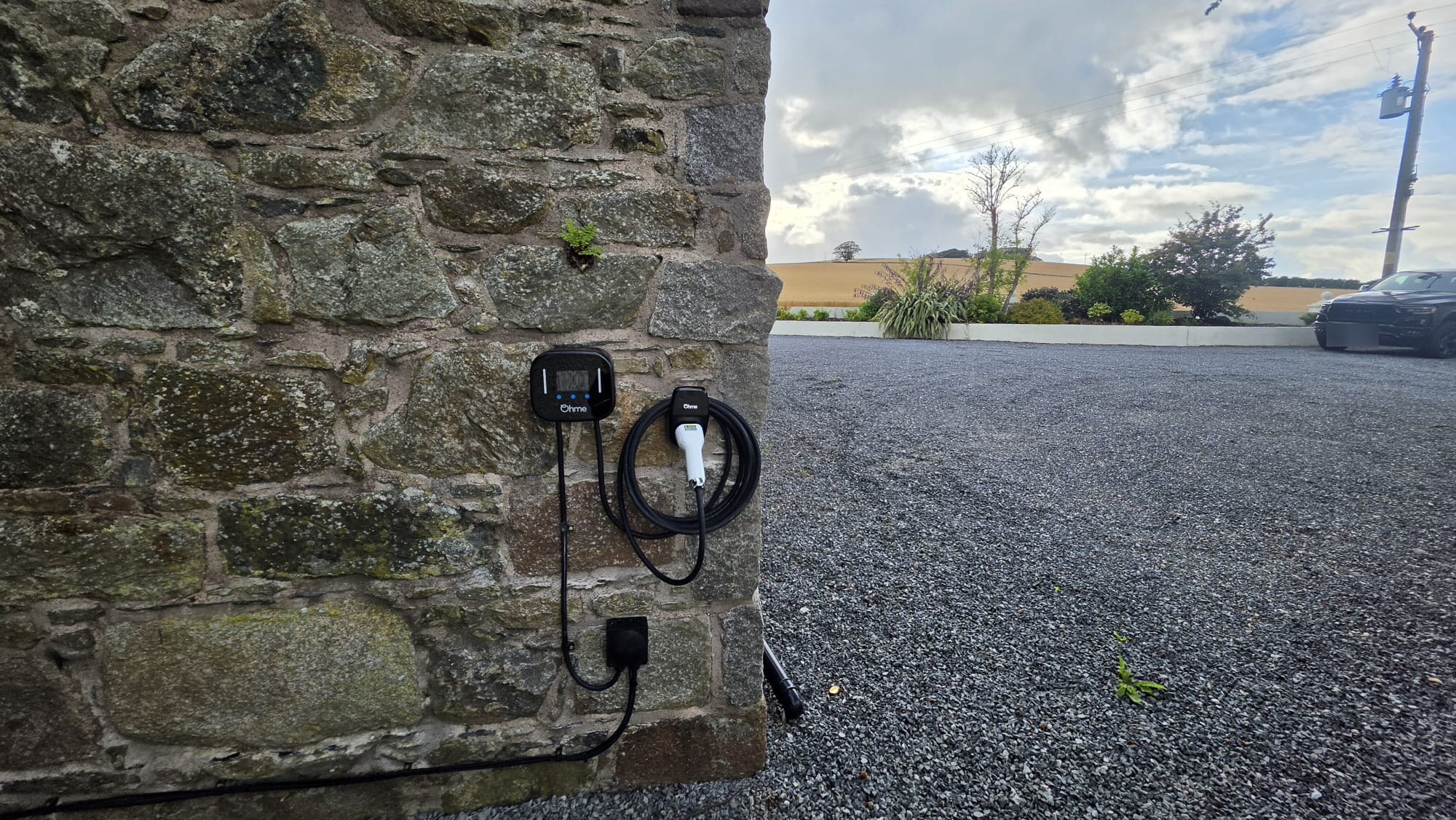Ohme EV charger fitted to a granite stone wall at a gravel driveway in Ellon